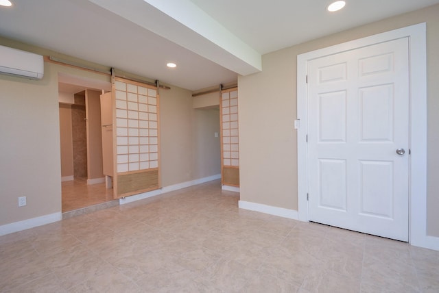 interior space featuring a wall mounted air conditioner, a barn door, baseboards, and recessed lighting