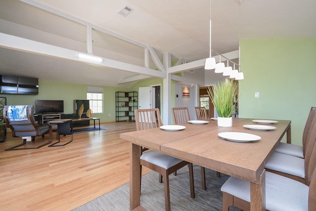 dining area with baseboards, visible vents, light wood-type flooring, and vaulted ceiling