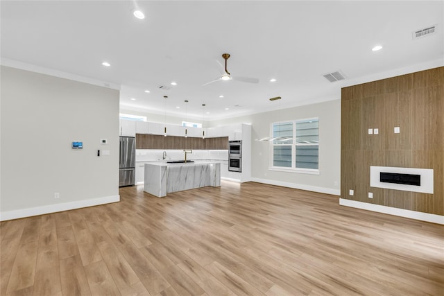 602 W 28th St Unit B, Houston, TX 77008 - unfurnished living room with ceiling fan, a sink, visible vents, light wood-style floors, and a large fireplace