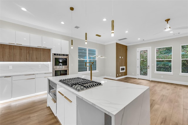 602 W 28th St Unit B, Houston, TX 77008 - kitchen with light wood finished floors, modern cabinets, white cabinetry, a kitchen island, and stainless steel appliances