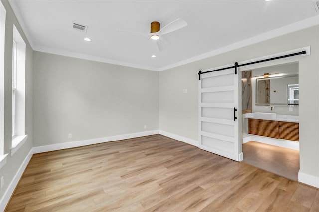 602 W 28th St Unit B, Houston, TX 77008 - unfurnished bedroom with crown molding, light wood-style floors, visible vents, and a barn door