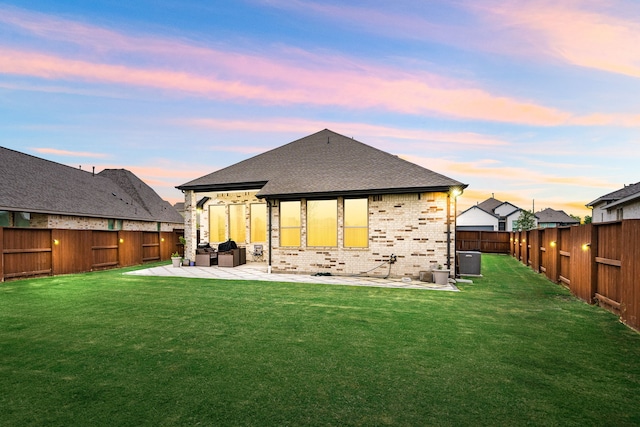 back of property with roof with shingles, a patio, brick siding, and central AC unit