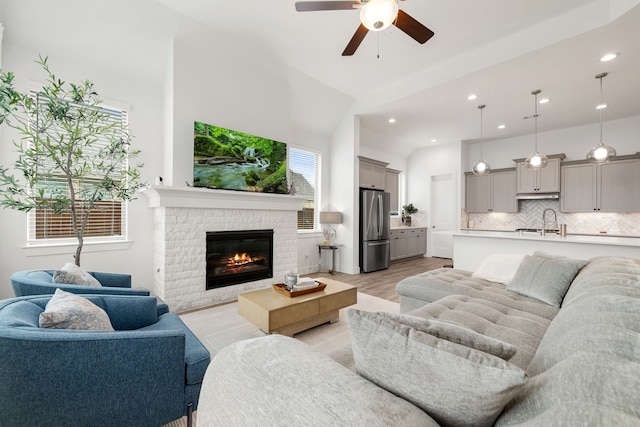 living area featuring a ceiling fan, recessed lighting, light wood-style floors, and a brick fireplace