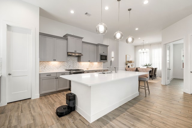 kitchen with gray cabinetry, light countertops, a sink, light wood-style floors, and recessed lighting