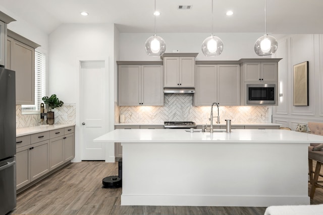 kitchen with gray cabinets, a sink, appliances with stainless steel finishes, tasteful backsplash, and light countertops