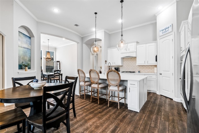 kitchen featuring a center island with sink, decorative backsplash, light countertops, dark wood-style floors, and white cabinets