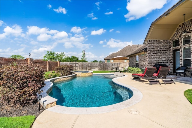view of swimming pool with a patio area, a pool with connected hot tub, and a fenced backyard