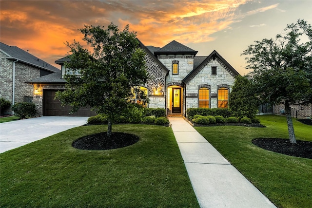 french country home featuring a yard, a garage, stone siding, and driveway