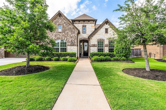 french country home with fence, a front lawn, and stone siding