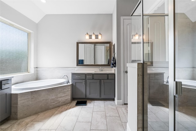 bathroom with a shower stall, vanity, a bath, and vaulted ceiling