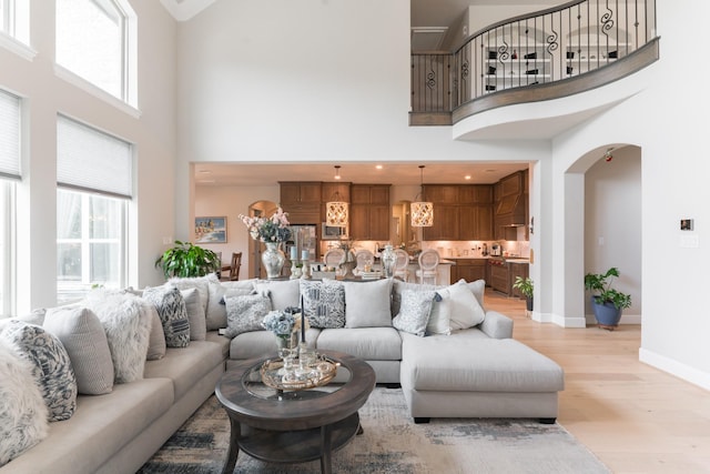 3923 Kelley Pond Dr, Spring, TX 77386 - living room with light wood-style flooring, baseboards, a high ceiling, and arched walkways