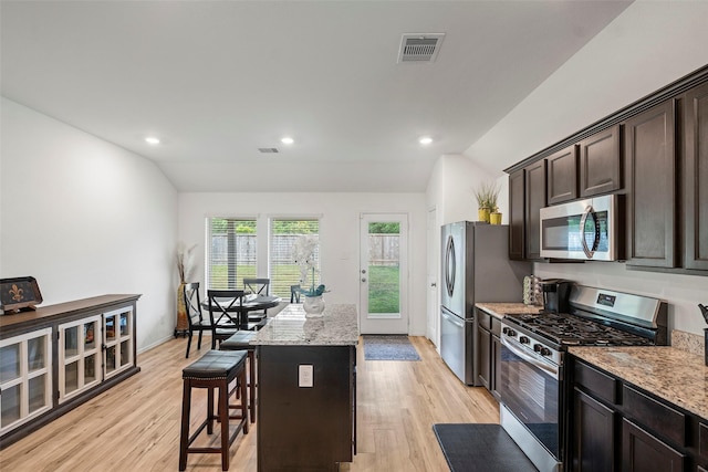 908 Pickering Oak Row, Magnolia, TX 77354 - kitchen featuring lofted ceiling, appliances with stainless steel finishes, a breakfast bar area, visible vents, and light wood-type flooring