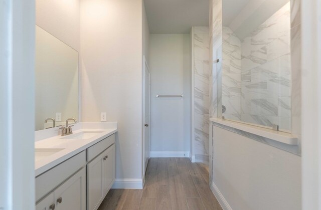 18711 Brego Ln, Tomball, TX 77377 - bathroom featuring a sink, walk in shower, wood finished floors, double vanity, and baseboards