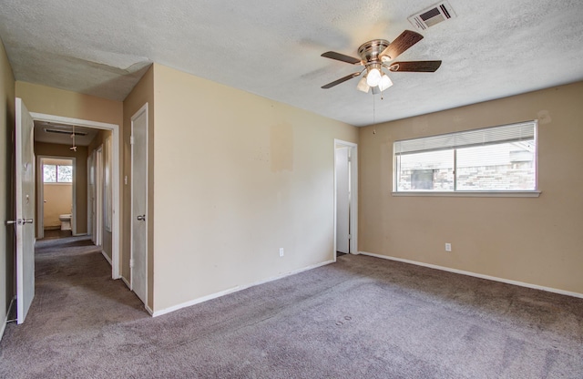 spare room with a ceiling fan, attic access, carpet floors, a textured ceiling, and visible vents