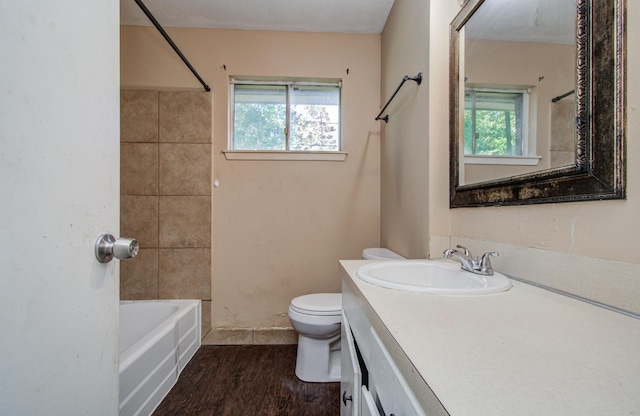 full bathroom with toilet, a healthy amount of sunlight, vanity, and wood finished floors