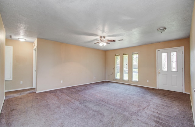 carpeted empty room featuring a textured ceiling, baseboards, and a ceiling fan