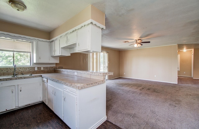 kitchen featuring a sink, open floor plan, a textured ceiling, white cabinetry, and ceiling fan