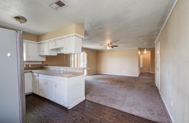 kitchen with freestanding refrigerator, visible vents, ceiling fan, white cabinets, and baseboards