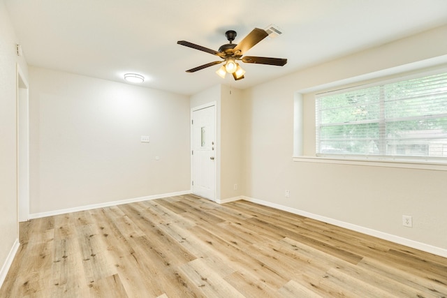 empty room with visible vents, wood finished floors, baseboards, and ceiling fan