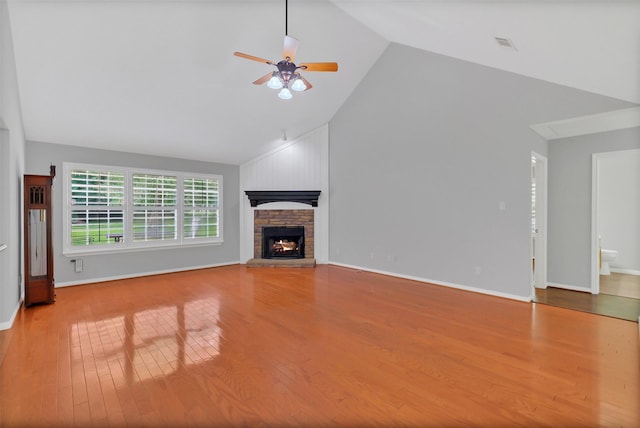 unfurnished living room featuring a ceiling fan, baseboards, high vaulted ceiling, wood finished floors, and a fireplace