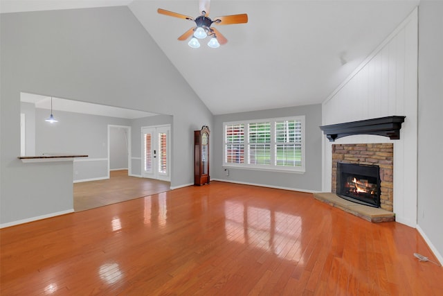 unfurnished living room featuring wood finished floors, a ceiling fan, high vaulted ceiling, a fireplace, and baseboards