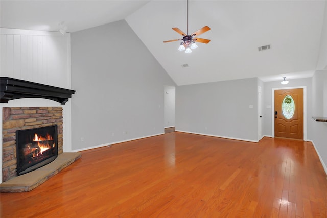 unfurnished living room featuring wood finished floors, high vaulted ceiling, visible vents, ceiling fan, and a stone fireplace