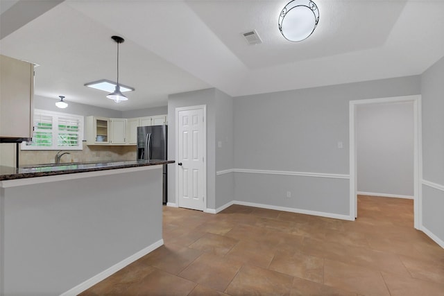 kitchen featuring dark stone counters, visible vents, pendant lighting, white cabinetry, and glass insert cabinets