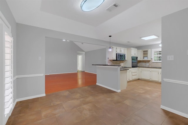 kitchen featuring a peninsula, black oven, dark countertops, visible vents, and stainless steel microwave