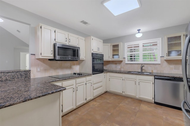 kitchen with backsplash, black appliances, dark stone countertops, and a sink