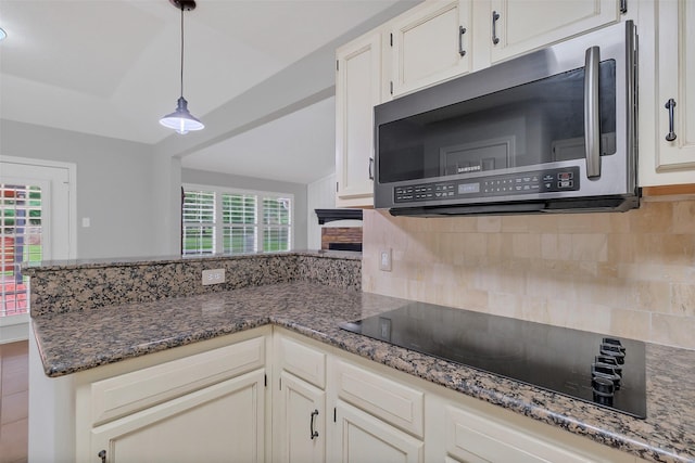 kitchen featuring stainless steel microwave, a peninsula, tasteful backsplash, white cabinets, and black electric cooktop