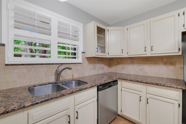 kitchen with a sink, stainless steel dishwasher, decorative backsplash, and dark stone countertops