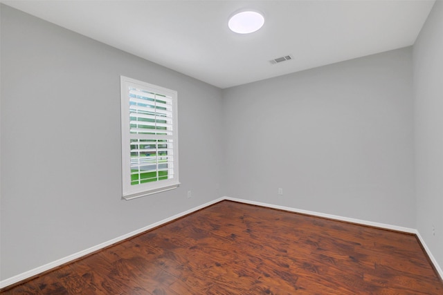 unfurnished room with baseboards, visible vents, and wood finished floors
