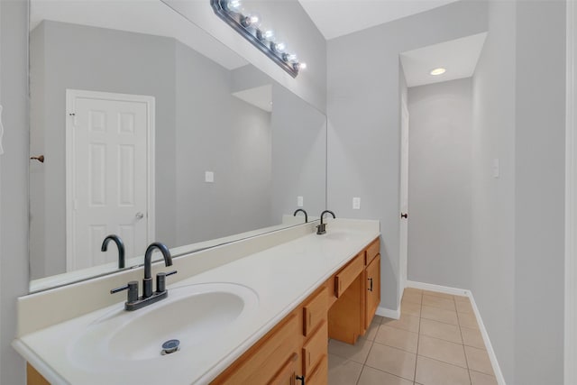 bathroom with a sink, tile patterned flooring, double vanity, and baseboards