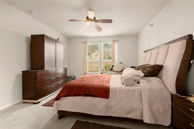bedroom featuring light carpet, ceiling fan, baseboards, and a textured ceiling