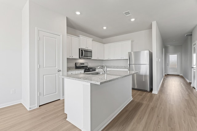kitchen featuring baseboards, light wood finished floors, a sink, white cabinetry, and appliances with stainless steel finishes