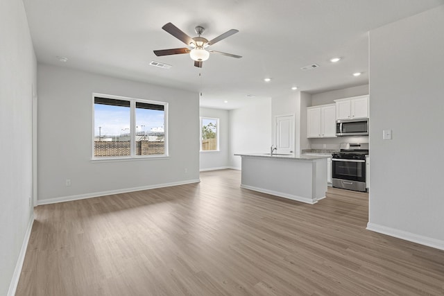 unfurnished living room featuring a sink, light wood-style flooring, and visible vents