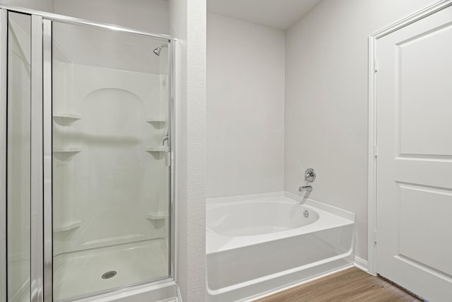 bathroom featuring a stall shower, a bath, and wood finished floors