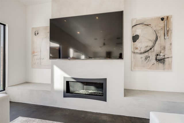 unfurnished living room featuring concrete flooring and a glass covered fireplace