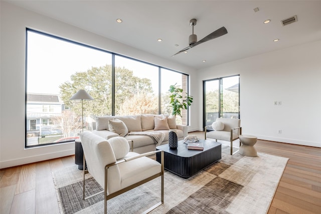living area featuring light wood-type flooring, ceiling fan, baseboards, and visible vents