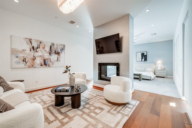 living room with recessed lighting, baseboards, a multi sided fireplace, visible vents, and wood finished floors