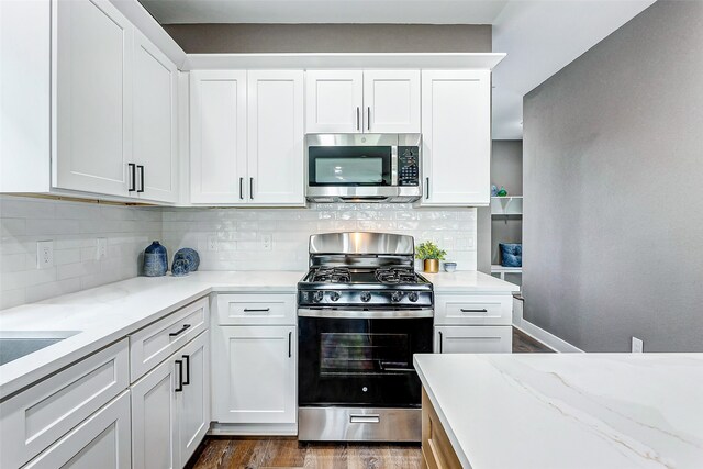kitchen featuring light stone countertops, stainless steel appliances, tasteful backsplash, and dark wood-type flooring