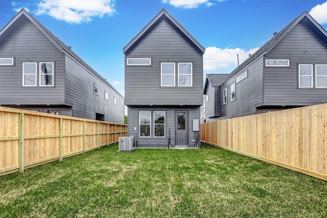 rear view of property featuring a lawn, central AC unit, and a fenced backyard