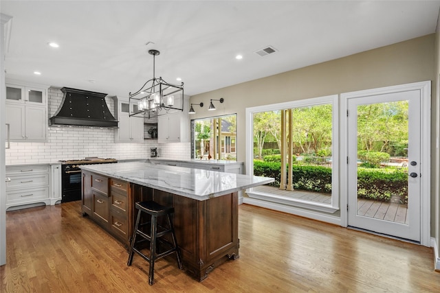 kitchen with gas range, premium range hood, white cabinets, backsplash, and recessed lighting
