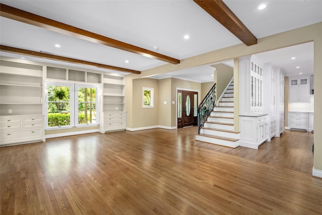 unfurnished living room featuring wood finished floors, beamed ceiling, baseboards, stairs, and recessed lighting