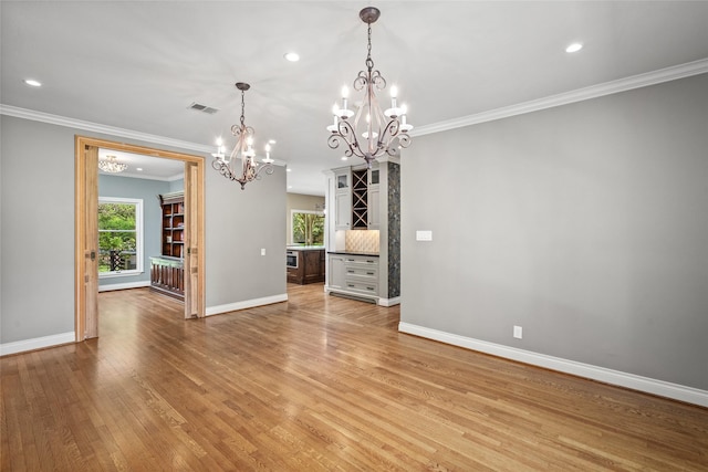 unfurnished dining area with a chandelier, ornamental molding, baseboards, light wood-type flooring, and recessed lighting
