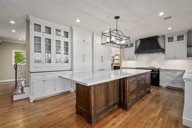 kitchen featuring custom range hood, gas range, white cabinetry, tasteful backsplash, and recessed lighting