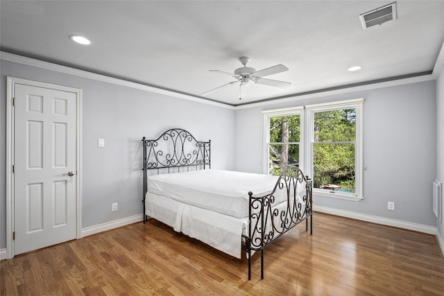 bedroom featuring baseboards, crown molding, wood finished floors, recessed lighting, and ceiling fan