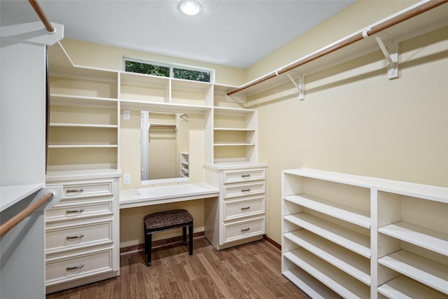 walk in closet featuring built in desk and dark wood finished floors