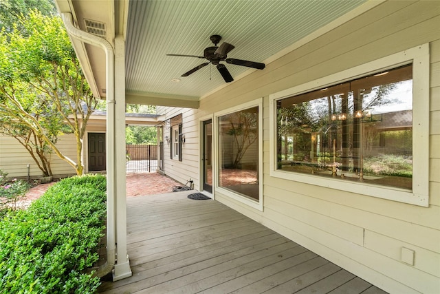 wooden terrace with a ceiling fan and fence