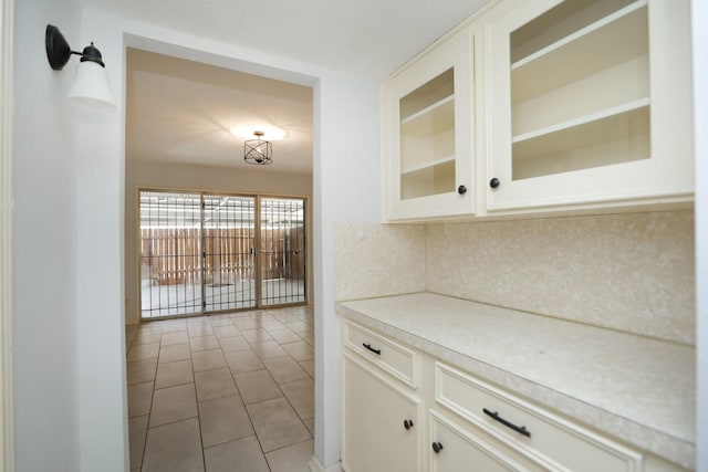 kitchen with light tile patterned floors, light countertops, white cabinets, and glass insert cabinets